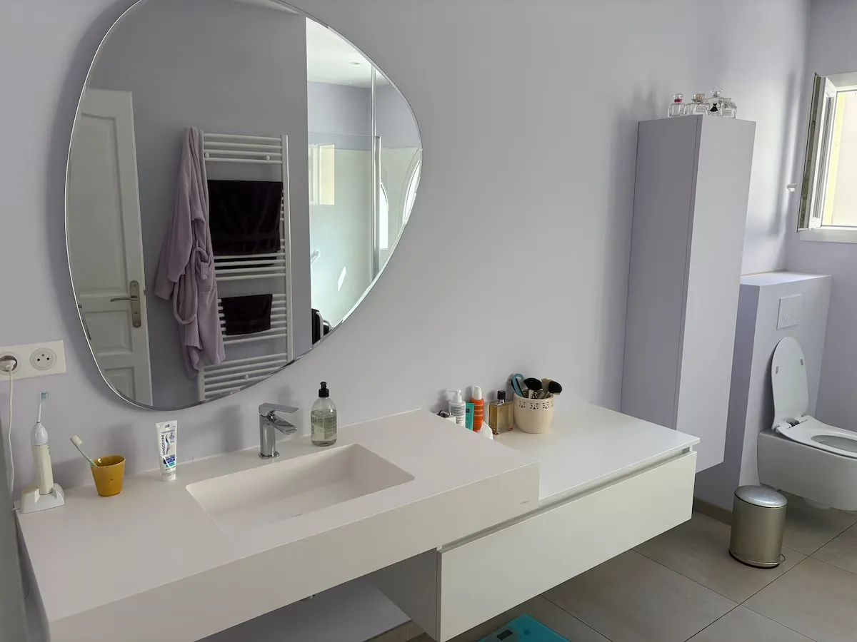 Salle de bain avec grande vasque et miroir rond à Montferrier-sur-Lez