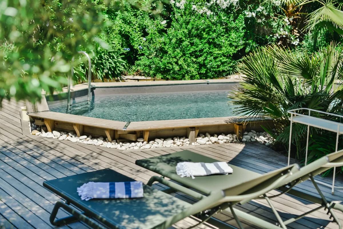 Terrasse en bois et bains de soleil au bord de la piscine à Castelnau-le-Lez